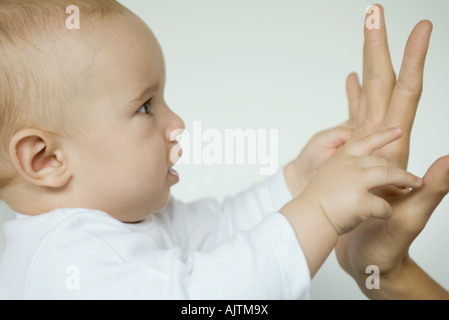 Baby raggiungendo per la madre la mano, in vista di profilo, close-up Foto Stock