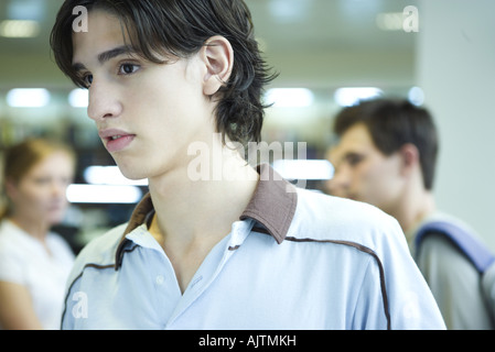 Maschio di studente di college in biblioteca, guardando lontano, la testa e le spalle Foto Stock