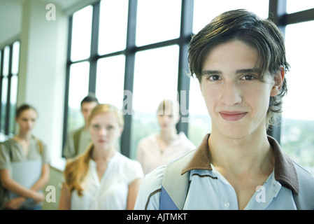 Un gruppo di studenti del college, concentrarsi sul giovane in primo piano, sorridente in telecamera Foto Stock