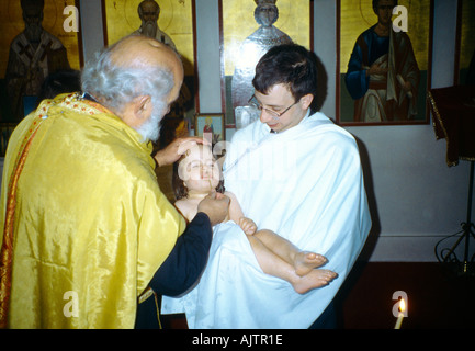 Kingston Surrey greco-ortodossa sacerdote battesimo facendo segno di croce sulla nuova bambino battezzato padrino Ricezione di bambino Foto Stock