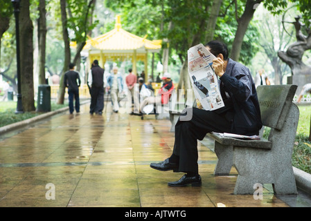 La Cina, nella provincia di Guangdong, Guangzhou, uomo quotidiano di lettura sul banco di lavoro Foto Stock