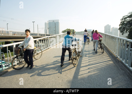 La Cina, nella provincia di Guangdong, Guangzhou, ciclisti attraversando ponte Foto Stock