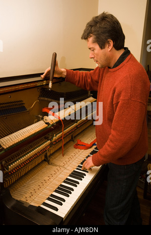 Sintonizzatore di piano al lavoro di messa a punto di un antico tedesco pianoforte verticale Foto Stock