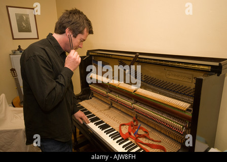 Sintonizzatore di piano al lavoro di messa a punto di un antico tedesco pianoforte verticale Foto Stock