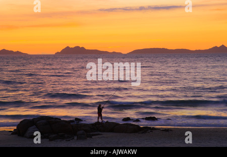 Fisherman stagliano sulla Playa de Samil spiaggia al tramonto Cies isola e una penisola de Morrazo in background Galizia Spagna Foto Stock