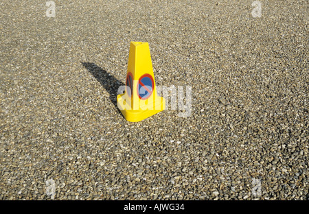 Un parcheggio non o cono di attesa seduta al centro di una distesa di vuoto di ghiaia parcheggio e getta un' ombra Foto Stock