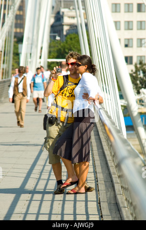 Ritratto verticale di giovani turisti visualizzazione delle loro fotografie dal retro di una fotocamera digitale su Charing Cross passerella Foto Stock