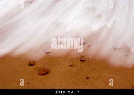 Spiaggia di sabbia e rocce rosse con la luce in entrata surf runoff patterns, Campbell's Cove, PE/PEI, Canada Foto Stock