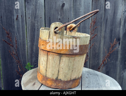 Vecchio secchio d'acqua di legno accanto a un fienile Foto Stock