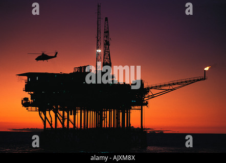 Australia. Stretto basso. Silhouette di elicottero sopra Southern Cross offshore petrolio rig al tramonto. Foto Stock