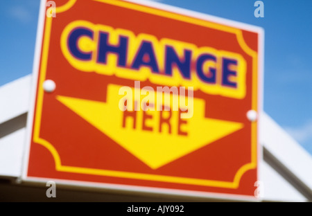 Close up di rosso giallo e il cartello blu con la freccia rivolta verso il basso contro il cielo blu e chiaro indicando modifica qui Foto Stock