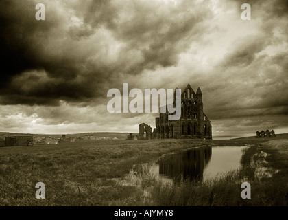 Whitby Abbey riflessa nello stagno e stagliano contro un cielo tempestoso Foto Stock