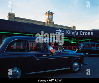 Regno Unito. In Inghilterra. Londra. Stazione di King Cross. Taxi driver guardando fuori della finestra laterale del suo black cab. Foto Stock