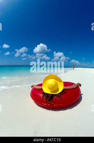 Turks Caicos Provo donna nel cappello giallo si trova in rosso tubo interno sulla spiaggia Foto Stock