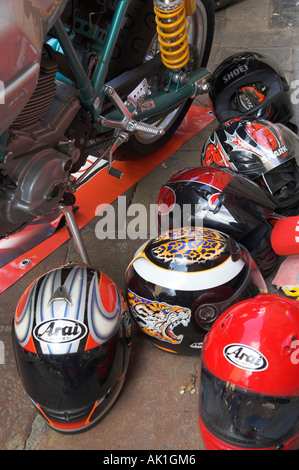 Gruppo di caschi moto sul terreno accanto alla ruota di bicicletta Foto Stock