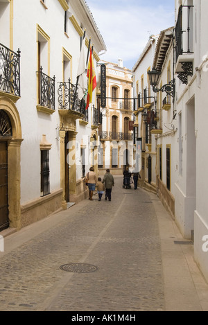 Due famiglie percorrendo a piedi uno dei tyically strette e tortuose stradine a Ronda, Spagna. Foto Stock