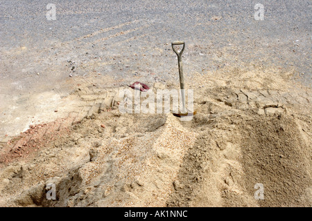 Pala di costruttori integrati in sabbia con scartato guanto di gomma Foto Stock