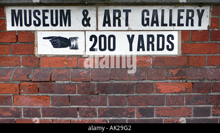 Vittoriano segno ceramico incorporato nella parete di mattoni rossi di strada pubblica che indica la direzione per il Museo e Galleria d'arte Hove Inghilterra Foto Stock