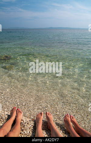I piedi femminili per prendere il sole sulla spiaggia a basso angolo vicino Mare Adriatico della costa della Dalmazia Croazia Foto Stock