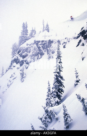 Uno sciatore salta fuori da un cornicione sulla cima di una scogliera ripida nel Cascade Mountains dello stato di Washington Foto Stock