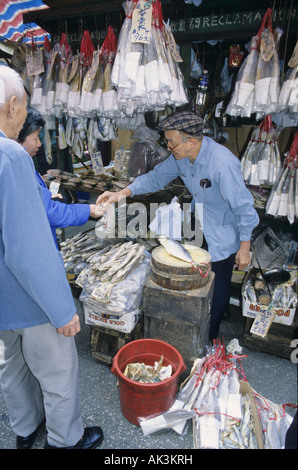 Il vecchio uomo cinese di vendita pesce essiccato ad una strada del mercato di Hong Kong Cina Foto Stock