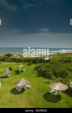 Vista da una finestra dell'albergo portobello verso la spiaggia di La paloma, Uruguay, con tavoli a baldacchino sul prato Foto Stock