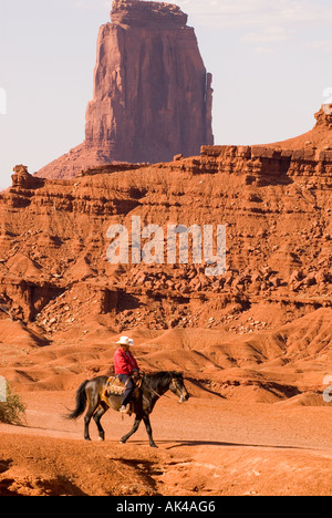 ARIZONA Monument Valley Navajo Tribal Park Native American Navajo cowboy a cavallo attraverso colorate di rosso altopiano di arenaria Foto Stock