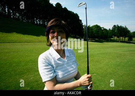 Donna che mantiene golf club, sorridente Foto Stock
