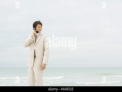 Imprenditore tramite telefono cellulare sulla spiaggia Foto Stock