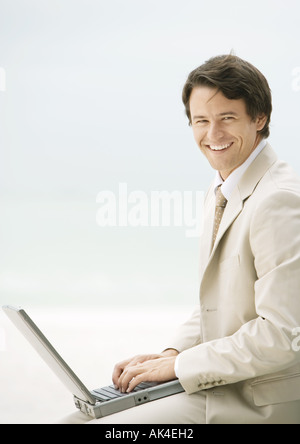 Uomo d affari con computer portatile, sorridente in telecamera Foto Stock