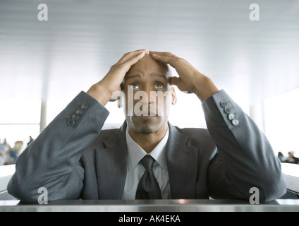 Imprenditore cercando e tenendo la testa in aeroporto Foto Stock