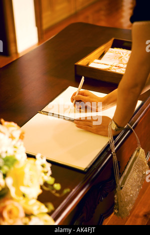 Close-up di donna Firma il libro degli ospiti Foto Stock
