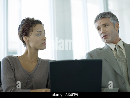 Due colleghi di lavoro avente la discussione e utilizzando computer portatile Foto Stock