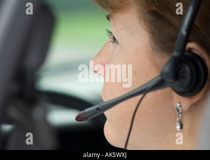 Giovane donna parlando al cellulare auricolare in auto Foto Stock