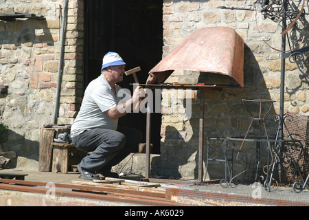 Lavoratore di metallo battendo un pannello nelle Marche ,Italia Foto Stock