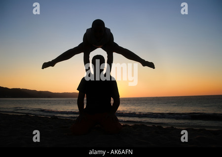 Due uomini sagome al tramonto sulla spiaggia Foto Stock