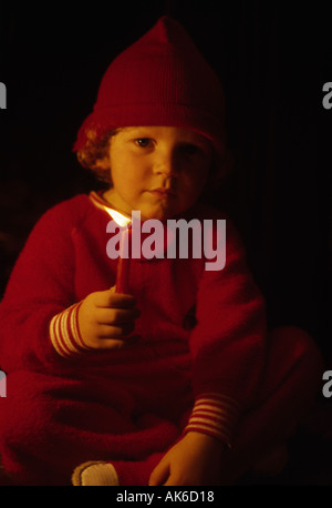 Santas helper tenere una candela accesa nel buio della notte di Natale Foto Stock