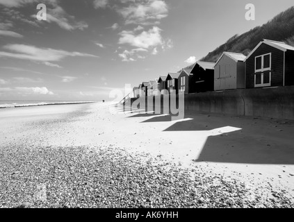 Beach Hut fino sul lungomare che si affacciano sul mare del Nord con spiaggia di sabbia riportata di seguito e la persona in formazione mono alta tasto effetto,Cromer Foto Stock