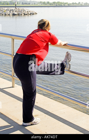 Adulto femaleperfroming esercizi di stretching prima della sua corsa mattutina Foto Stock