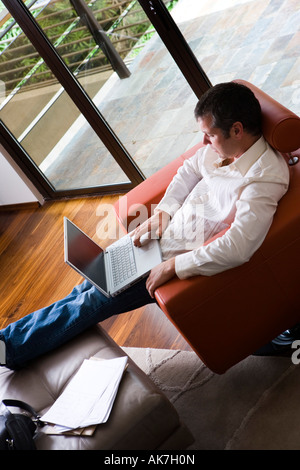 Uomo al lavoro su laptop in Soggiorno moderno Foto Stock