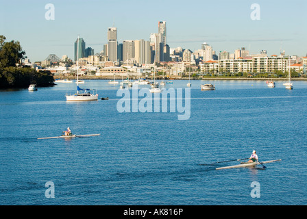 La mattina presto i canottieri sulla Hamilton raggiungere il fiume Brisbane centro di Brisbane in background Queensland Australia Foto Stock