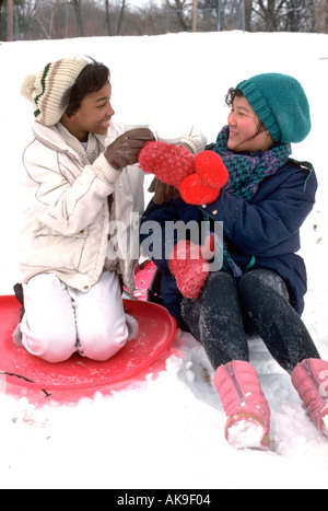 Americano di origine coreana e nero amico età 11 e 13 sulle slitte tostare con cacao. Città e Paese Campo da Golf St Paul Minnesota USA Foto Stock