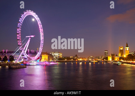 Vista del London Eye e le case del Parlamento lungo il Tamigi da Hungerford Bridge di notte, Londra Foto Stock