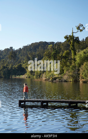 Bambino sul pontile Lago Mapourika costa ovest di Isola del Sud della Nuova Zelanda Foto Stock