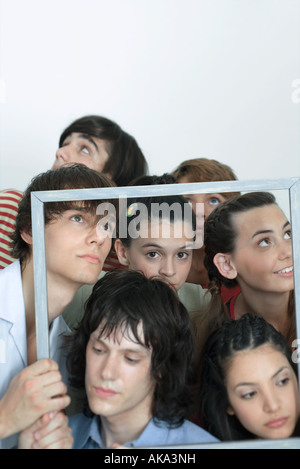 Un gruppo di giovani amici mantenendo la cornice immagine, cercando in direzioni differenti, ritratto Foto Stock