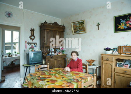 Senior donna seduta in home interno Foto Stock