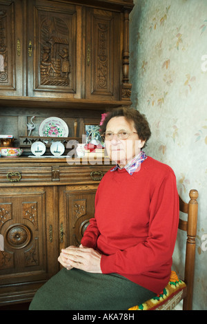 Senior donna seduta in home interno Foto Stock