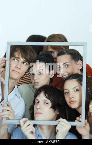Un gruppo di giovani amici che posano per una foto, tenendo su Picture Frame, guardando la telecamera, ritratto Foto Stock