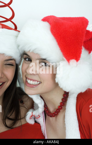 Due giovani amici di sesso femminile vestito in costumi di Natale, sorridente in telecamera, ritratto Foto Stock