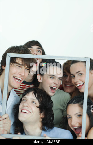 Un gruppo di giovani amici che posano per una foto, tenendo su Picture Frame, ridere, ritratto Foto Stock